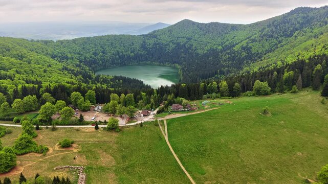 Aerial drone view of a round crater lake in a forested hollow, Lacul Sfanta Ana, Harghita, Transylvania, Romania.
