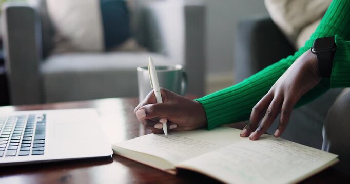 Concentrated Black Female Hands Writing Notes in a Notebook on a Desk with a Laptop and Mug