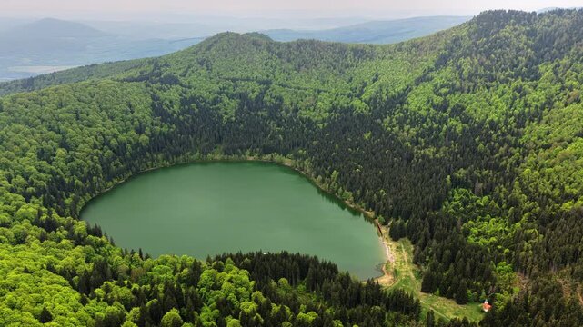 High-altitude aerial view of a round crater lake encircled by forest, Lacul Sfanta Ana, Harghita, Transylvania, Romania.