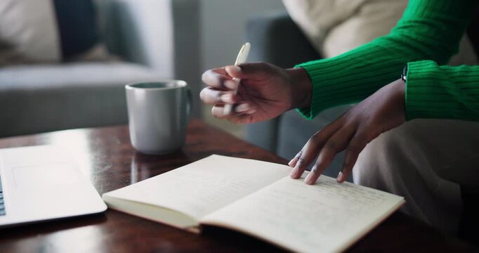 Close-Up Of A Black Woman's Hands Writing And Studying In A Notebook At Home With A Laptop