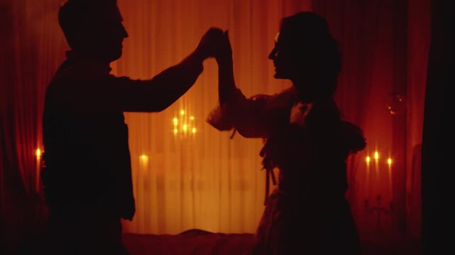 Black unrecognizable silhouette two gothic person, happy dancing together man king holding hand noble woman queen. Night dark room candles light. Adult girl guy old style, medieval ball themed party