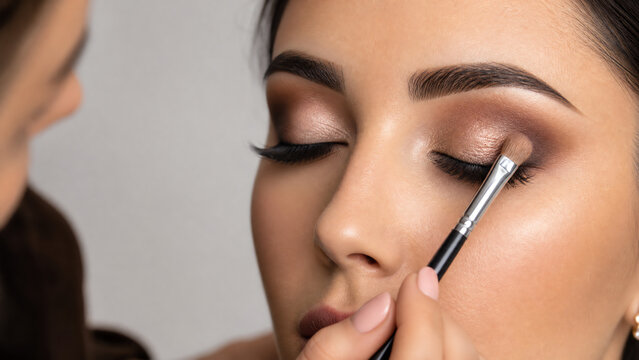 A close-up of a woman receiving professional makeup application highlighting beauty and artistry.