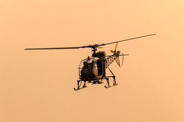 Fototapeta premium Silhouette helicopter flying towards me on isolated sky during dawn