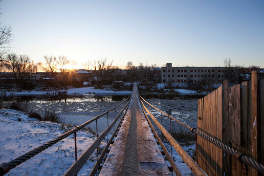 A suspension bridge over the Msta River in winter, on a sunny day. Borovichi, Novgorod Oblast, Russia.