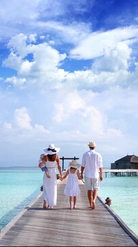 A elegant family of four enjoys their tropical vacations in the Maldives islands as a concept for travel and vacations with copy space