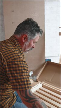 Tattooed man assembling flat pack furniture