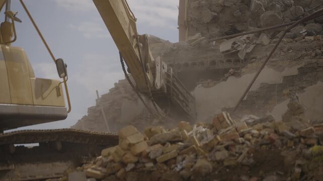 Dust flies from the destruction of the wall by the hydraulic hammer of the excavator