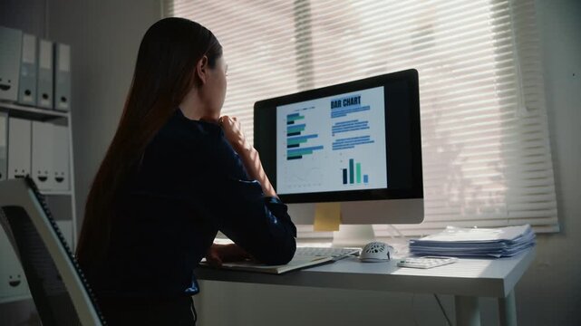 Overworked female employee experiencing burnout and stress while working on a computer in a modern office. Tired professional feeling sick