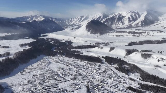 Aerial view of mountain village surrounded by snow and peaks Xinjiang
