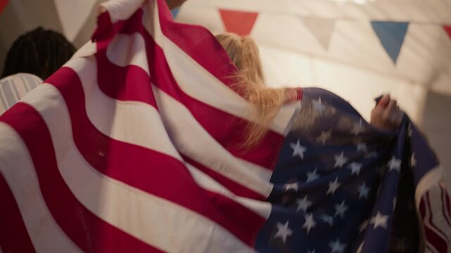 Low angle shot of multiethnic young adults celebrating Independence Day, with Caucasian woman wrapped around USA flag. Footage is perfect for patriotic holiday marketing campaigns and ads