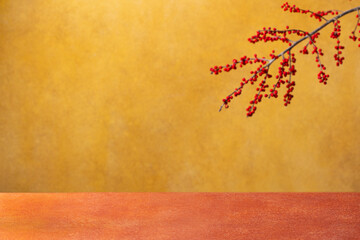 Obraz premium Mustard Yellow and Burnt Orange background with festive red berries and empty wooden surface for decoration. Copy space.