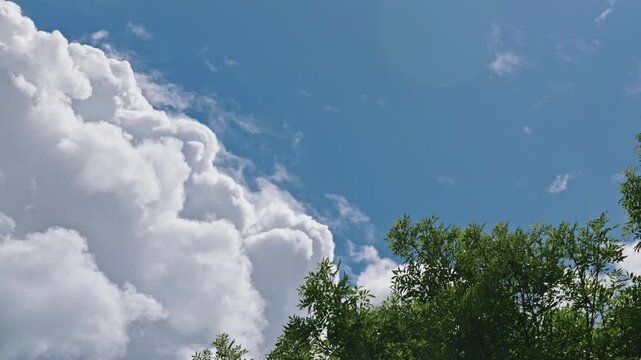 Bright blue sky with massive soft clouds changing shapes in real time