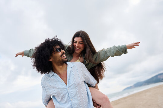 Smiling couple enjoying piggyback ride on beach