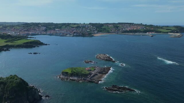 Scenic aerial view flying over Isla del Carmen and the coastal town of Luanco in Asturias, Spain