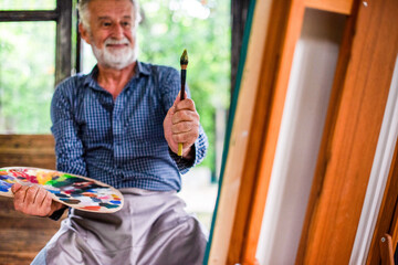 Senior white man painting in studio, holding brush and palette © Rawpixel.com