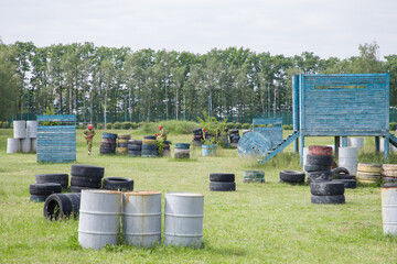 Paintball field with barrels, old tires and blue painted wooden crates for paintball game in summer day © Таня Микитюк