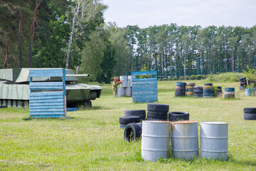 Paintball field with barrels, old tires and blue painted wooden crates for paintball game in summer day © Таня Микитюк
