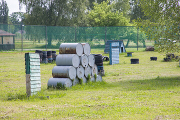 Paintball field with barrels, old tires and blue painted wooden crates for paintball game in summer day © Таня Микитюк