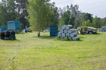 Paintball field with barrels, old tires and blue painted wooden crates for paintball game in summer day © Таня Микитюк
