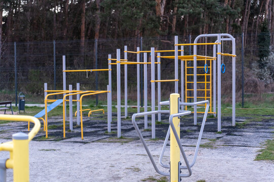 Empty outdoor calisthenics zone with yellow and grey pull-up bars, parallel bars and gymnastic rings. Concept of free street gym, active community lifestyle and sports infrastructure