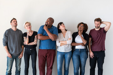 Obraz premium Diverse group of people standing thoughtfully against a white wall.