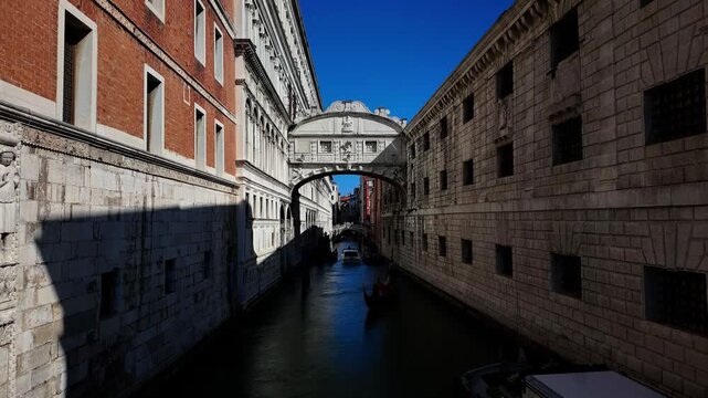 The iconic white limestone Bridge of Sighs over the narrow Rio di Palazzo canal in Venice, Italy, featuring classic architecture with dramatic sunlight and shadows.