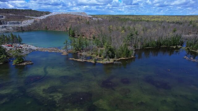 Turquoise lake water near open pit mine operation with sky. Mining operation, deep underground development of critical minerals for Artificial intelligence AI, EVs and hyperscale data centres.
