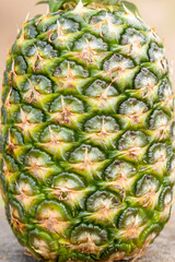 Fototapeta premium Macro view of pineapple skin texture with green and yellow scales and spikes. Tropical fruit surface pattern. Food photography. Design for packaging, poster, banner, wallpaper, textile, print.