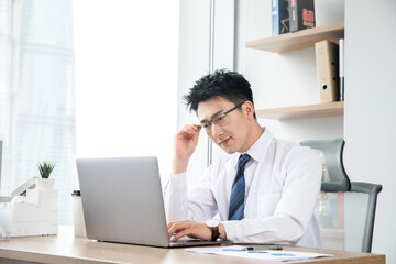 Naklejka premium Focused businessman working on laptop in modern office