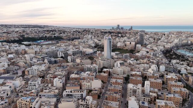 Aerial view of the dense urban landscape featuring modern skyscrapers and traditional limestone architecture under a soft sky in Msida, Eastern Region, Malta.