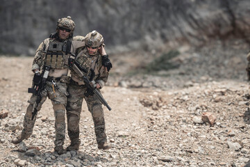 Obraz premium Soldiers assisting an injured teammate during a military field operation, demonstrating teamwork, rescue support, tactical coordination, leadership, endurance, and mission readiness in a challenging 