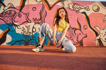 Young woman posing by colorful street mural with urban fashion style © TuBichHong