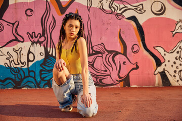 Fashionable young woman posing by colorful street mural © TuBichHong
