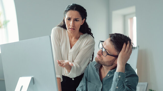 Worried Hispanic Woman And Man Displaying Concern While Observing Computer Screen Together, Engaged In Discussion About Work Projects At Office, Fostering Collaboration In Business Concept
