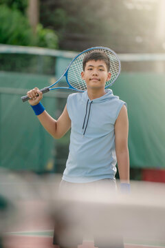 A boy is on the tennis court to play tennis.