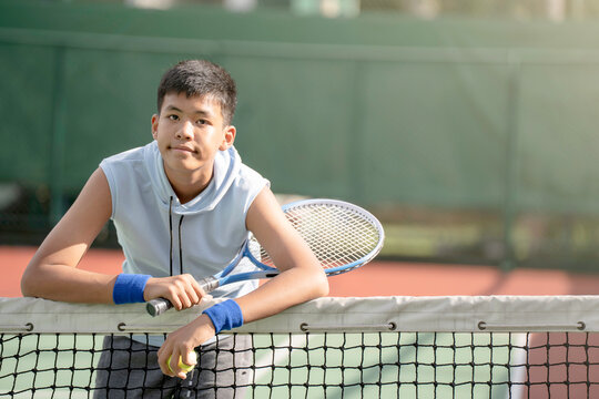 A boy is on the tennis court to play tennis.