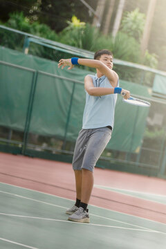 A boy is on the tennis court to play tennis.
