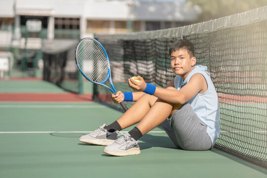 A boy is on the tennis court to play tennis.