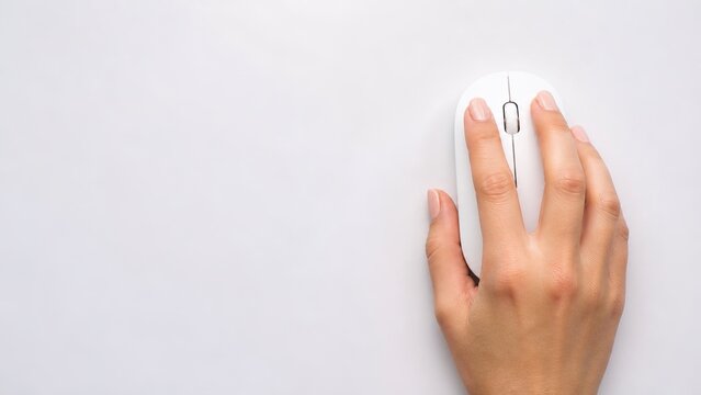 Hand using computer mouse on white surface for productivity in home office minimalist environment close-up view emphasizing technology and efficiency