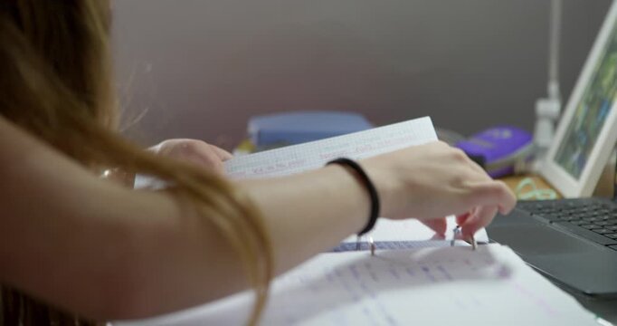 Student Studying: A student diligently studies, hands turning pages of a textbook while a laptop is open nearby. The scene captures the focus and effort involved in learning.