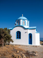 Obraz premium White and blue Greek Orthodox chapel by the sea in Ikaria island under blue summer sky, Greece