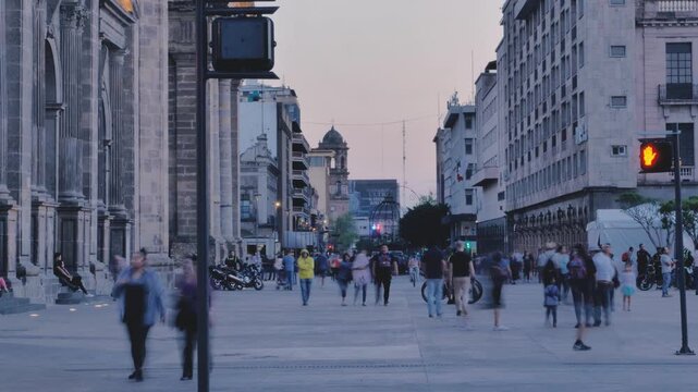 Street with people walking at dusk
Street with old buildings, with many people walking from one side to the other, signs and cars passing nearby, as it gets dark.