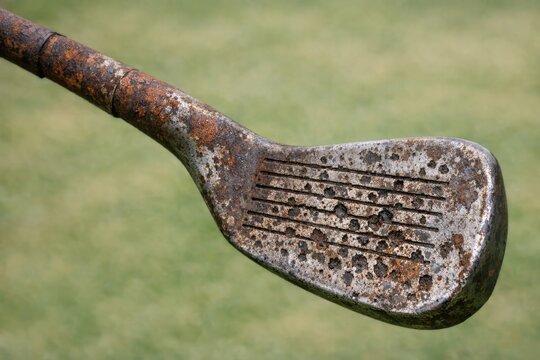 A damaged golf club with rusty metal and holes
