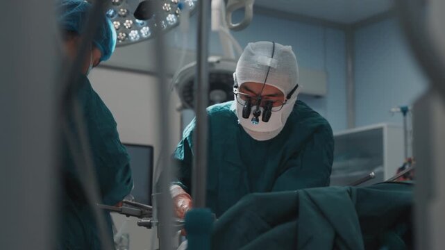 Close-up of a focused surgeon wearing magnifying surgical loupes while performing a complex operation in a modern operating room. Healthcare, surgery, precision medicine, professional expertise and ho