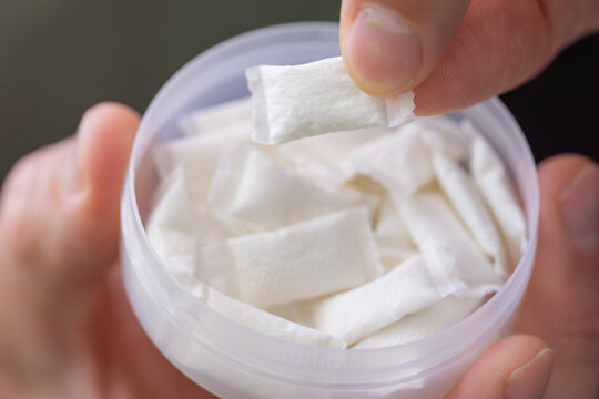 taking nicotine pouch background plastic box surface close up of hands holding white snus portion swedish tobacco free alternative smokeless product concept of addiction, bad habits, nicotine delivery