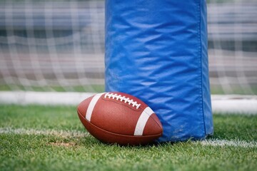 A football lies on a grassy field next to a blue bag, ready for play or transport