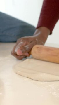 Vertical video: Rolling hands in sweater after dough placed, pressing pin on floured top to bake