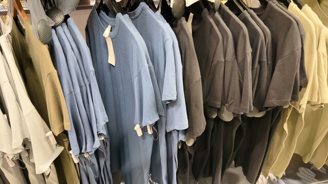 Colorful blank t-shirts hanging on clothing rack in retail store, basic cotton shirts collection, fashion apparel display