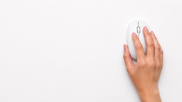Close up of a woman hand using a wireless computer mouse on a clean minimalist background with copy space. Concept of technology, digital navigation, online work, remote office.