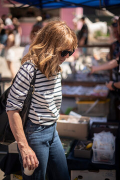Stylish midlife woman browsing items at outdoor flea market on a sunny day